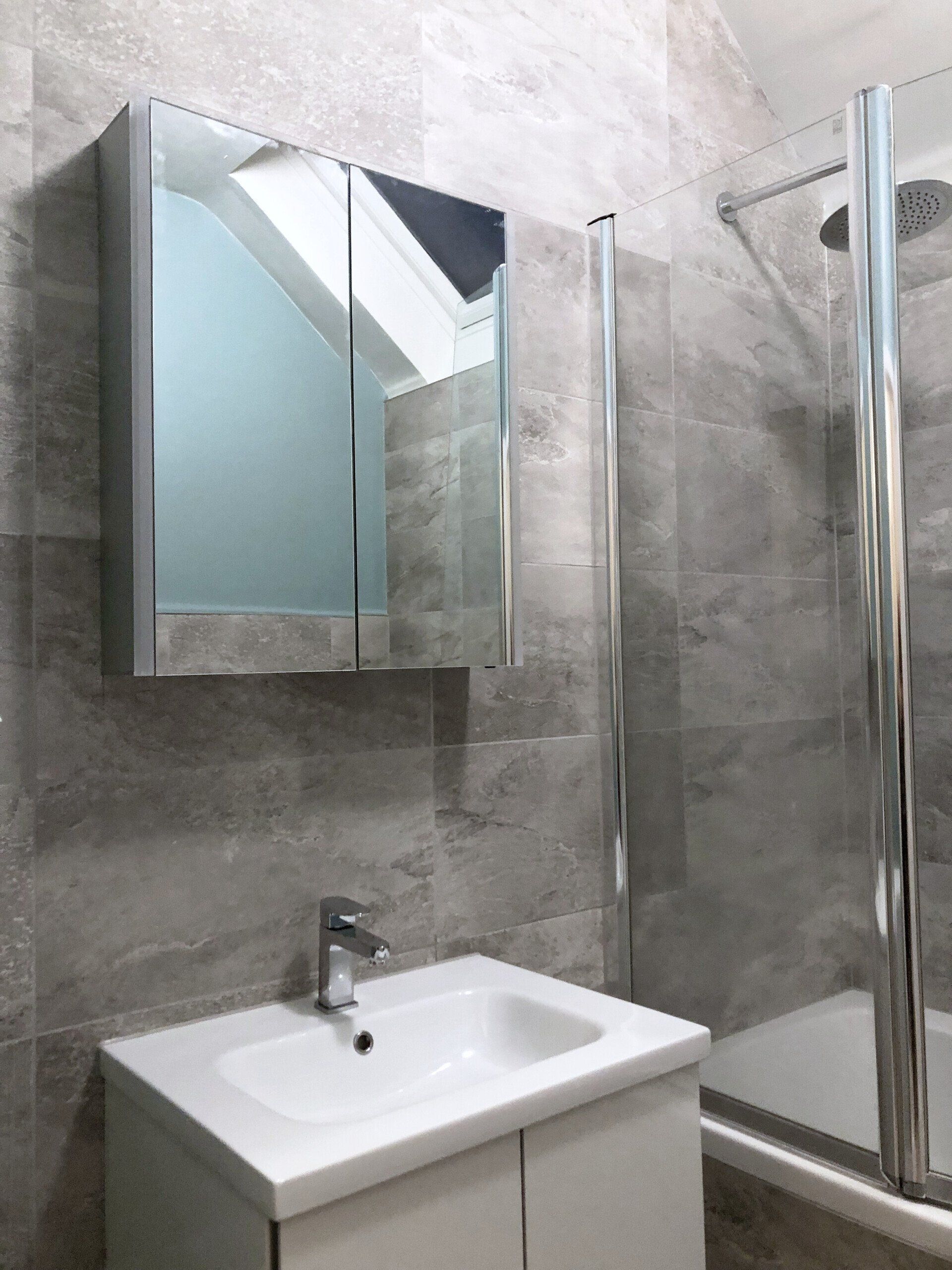 A bathroom with a sink , mirror and shower.