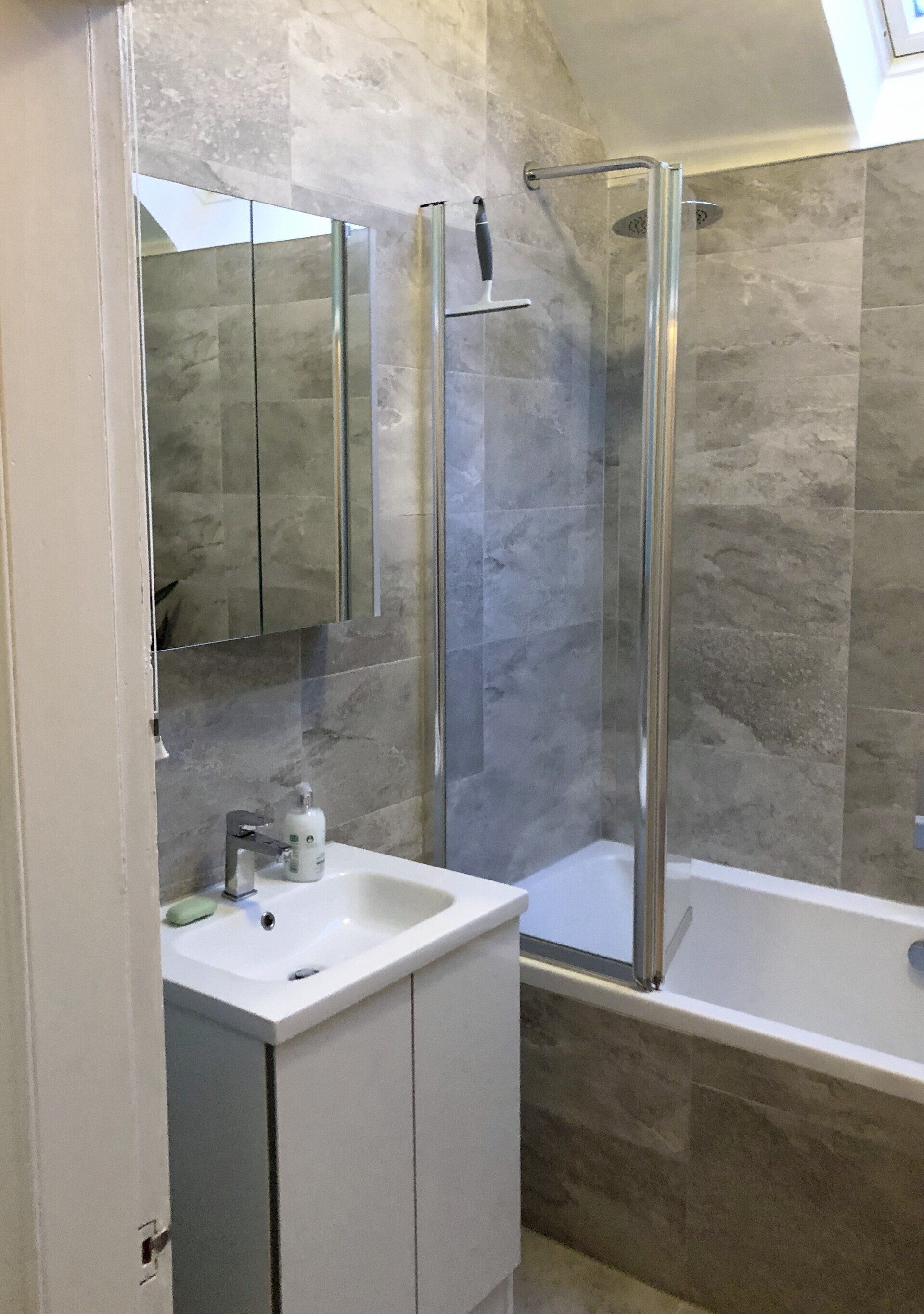 A bathroom with a sink , tub , shower and mirror.