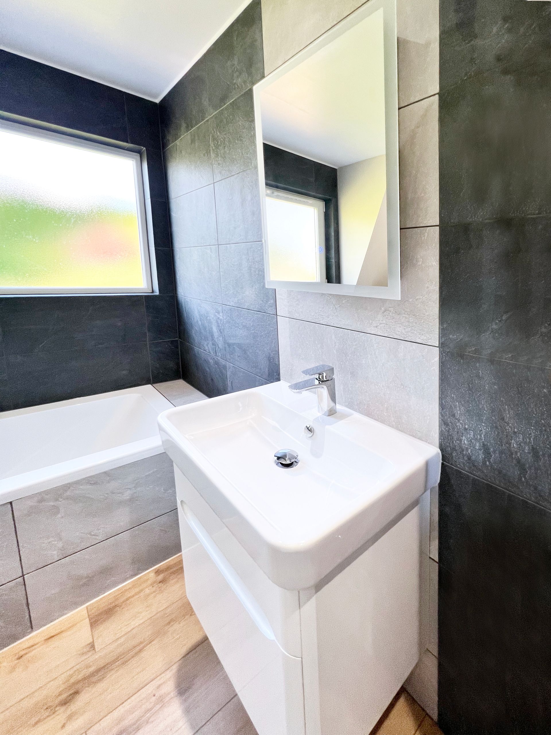 A bathroom with a sink , mirror and bathtub.