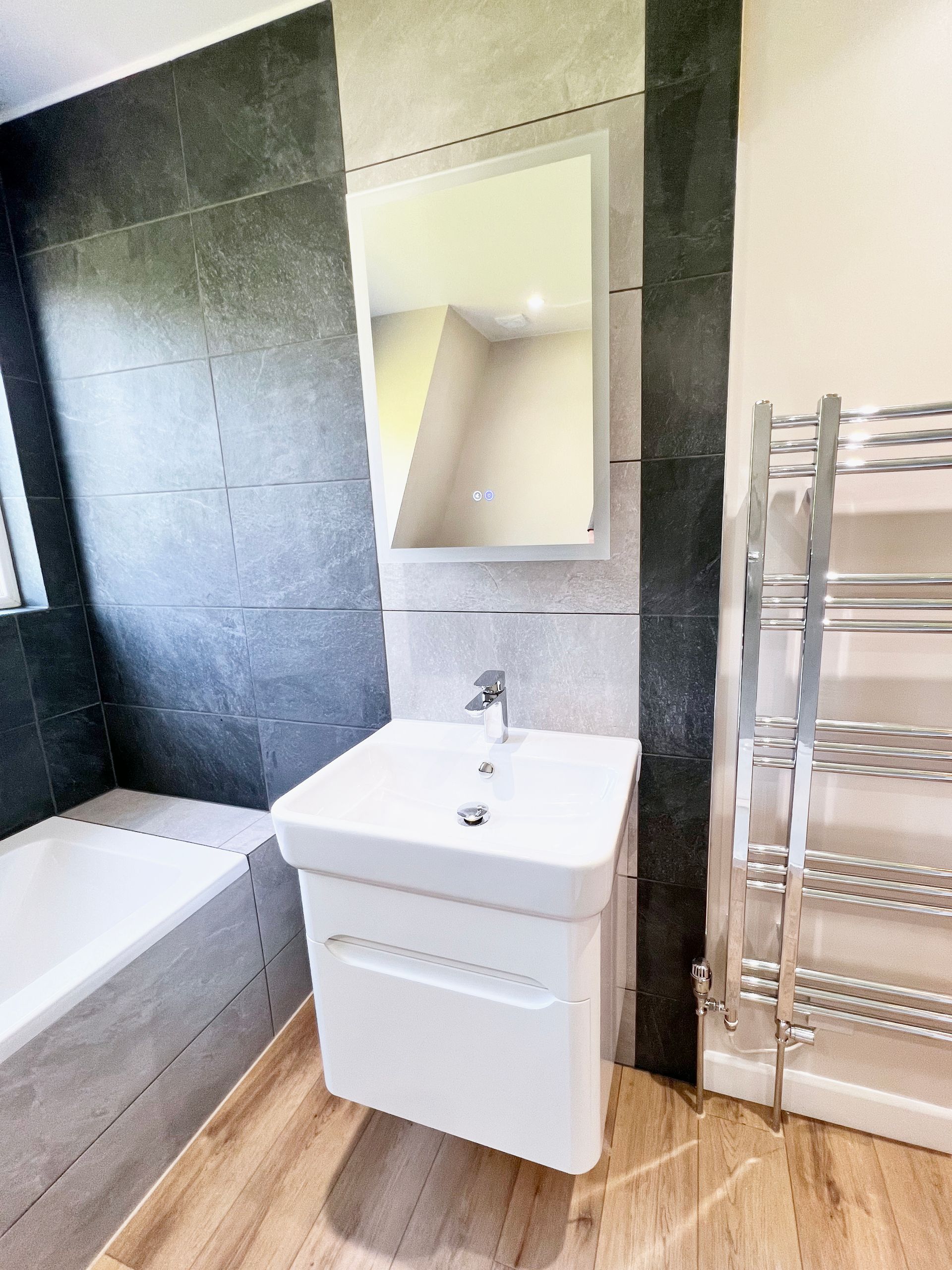 A bathroom with a sink , mirror and towel rack.