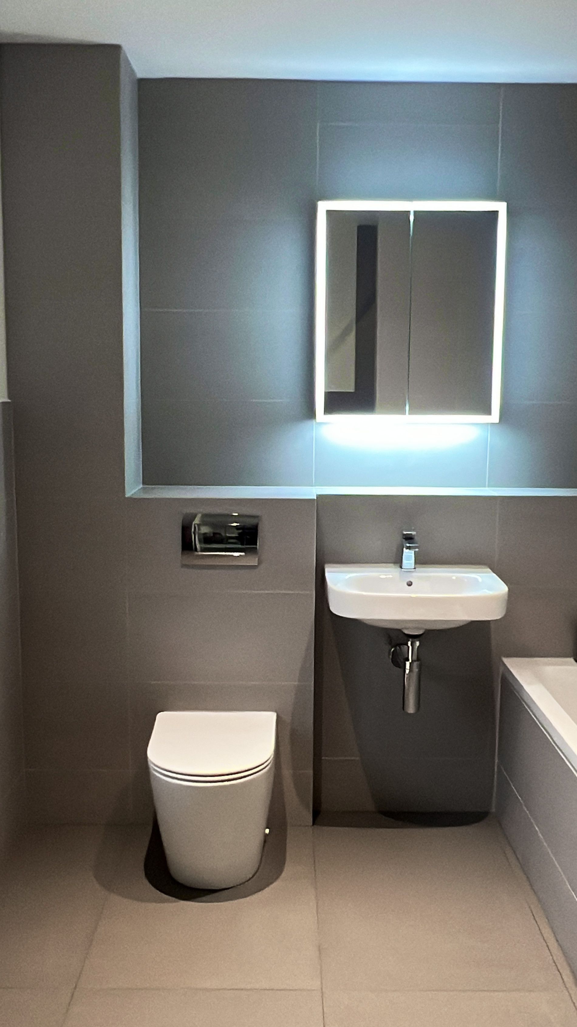 A bathroom with a toilet , sink , mirror and bathtub.