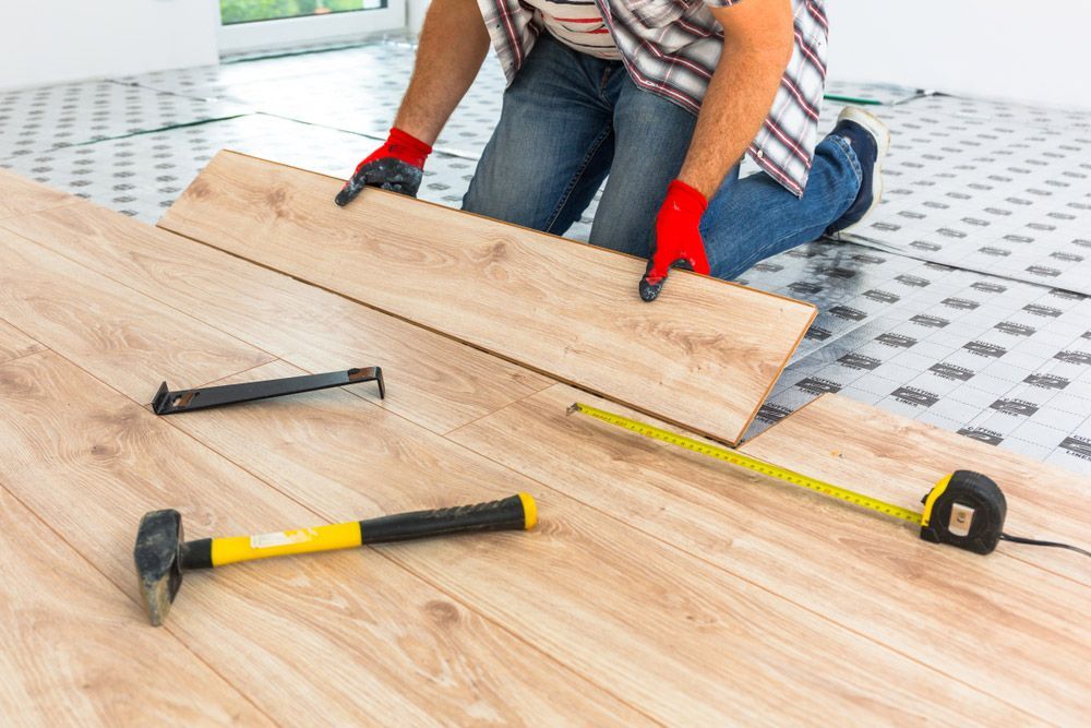 A Man Is Installing A Wooden Floor In A Room — Byron Floor Sanding In Norther Rivers, NSW
