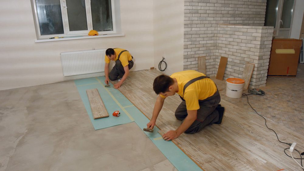 Two Men Are Working On A Wooden Floor In A Living Room — Byron Floor Sanding In Casino, NSW