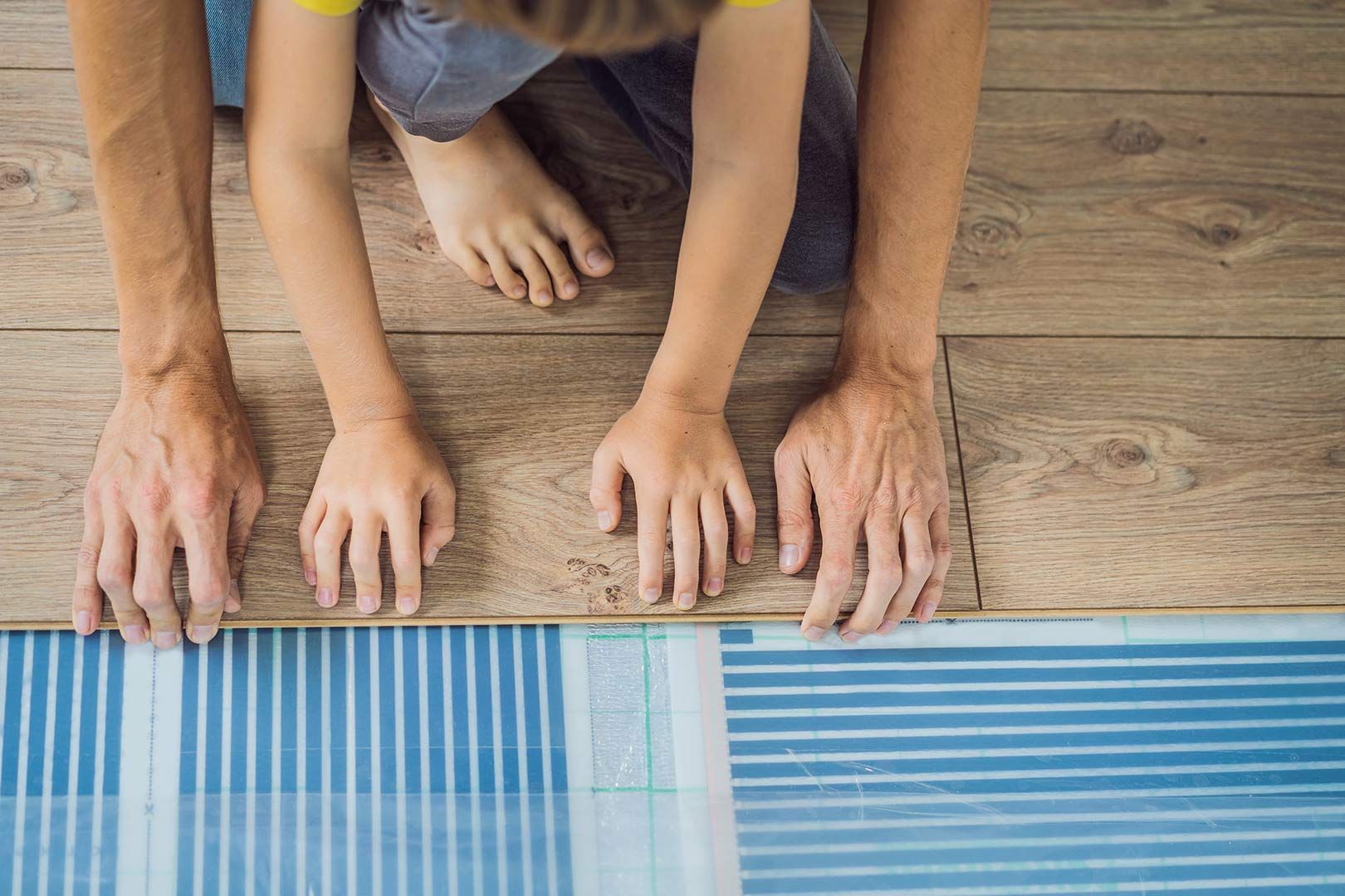 A Man And A Child Are Installing A Heated Floor — Byron Floor Sanding In Norther Rivers, NSW