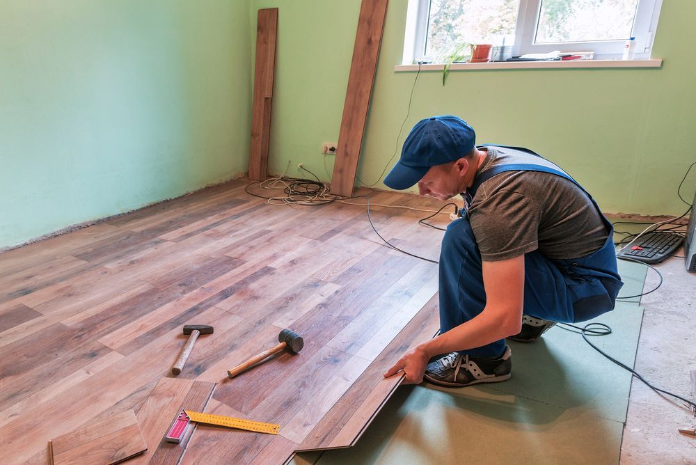 A Man Is Installing A Wooden Floor In A Room — Byron Floor Sanding In Yamba, NSW