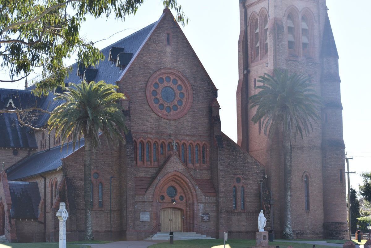 A Large Brick Church With A Palm Tree In Front Of It — Byron Floor Sanding In Lismore, NSW