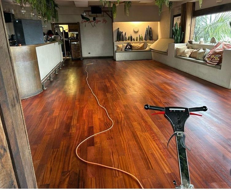 A Room With Polished Floors and Polish Machine and Power Cord with Couches — Byron Floor Sanding In Tintenbar, NSW