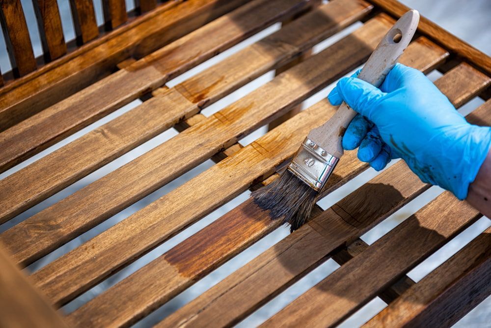 Person in Blue Glove Staining Wooden Bench with A Brush — Byron Floor Sanding In Norther Rivers, NSW