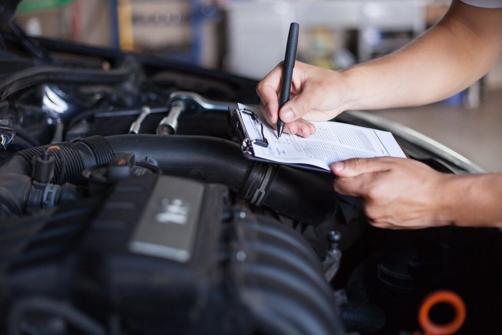 A Person is Writing on a Clipboard Under the Hood of a Car — Steve's Service Centre in Albury, NSW 