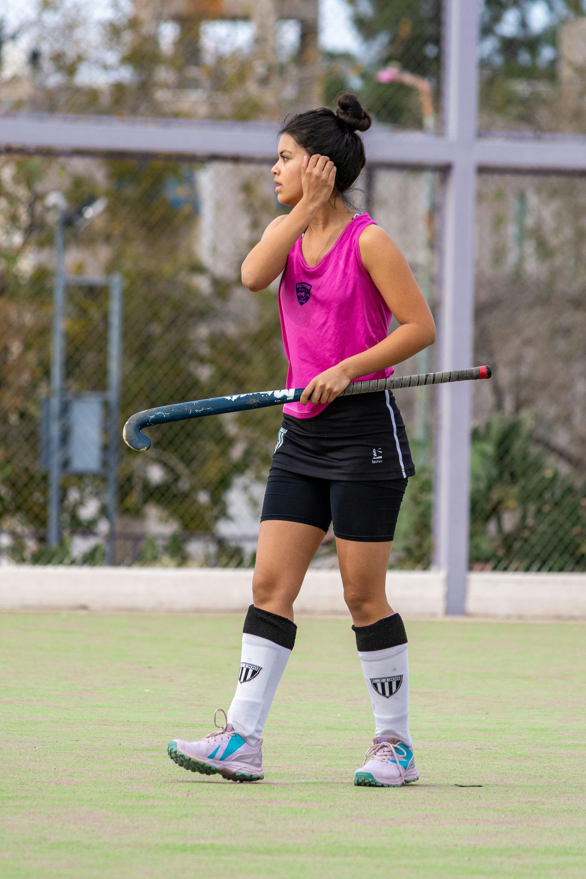 A woman is holding a hockey stick on a field.