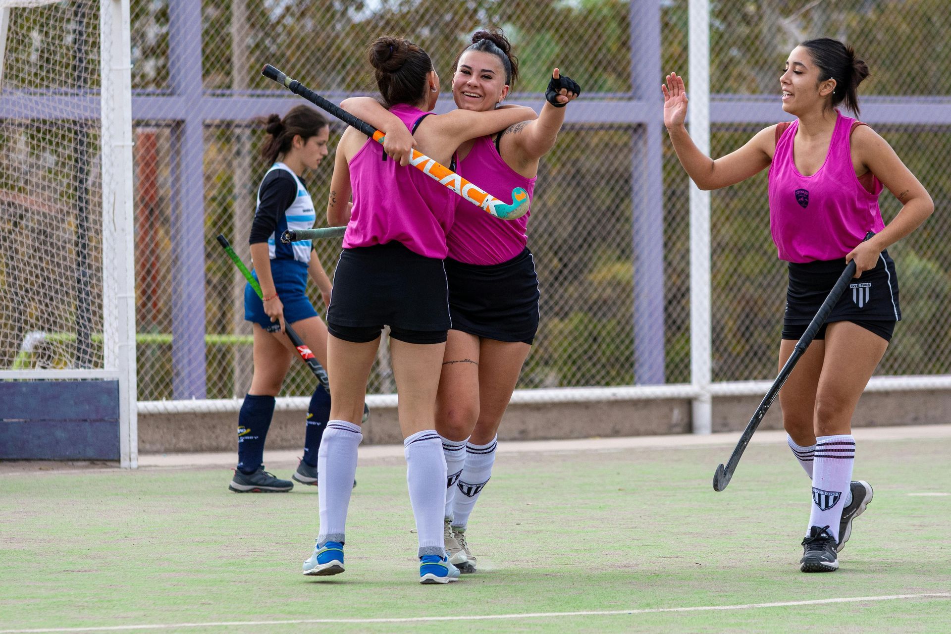 A group of women are playing field hockey on a field.
