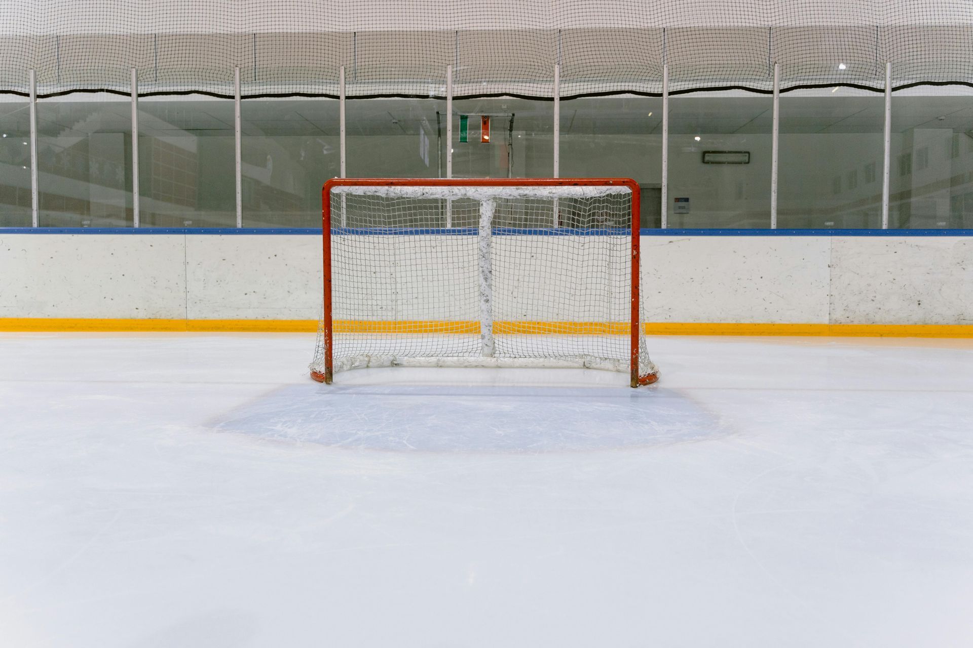 An empty hockey rink with a goal in the middle of it.