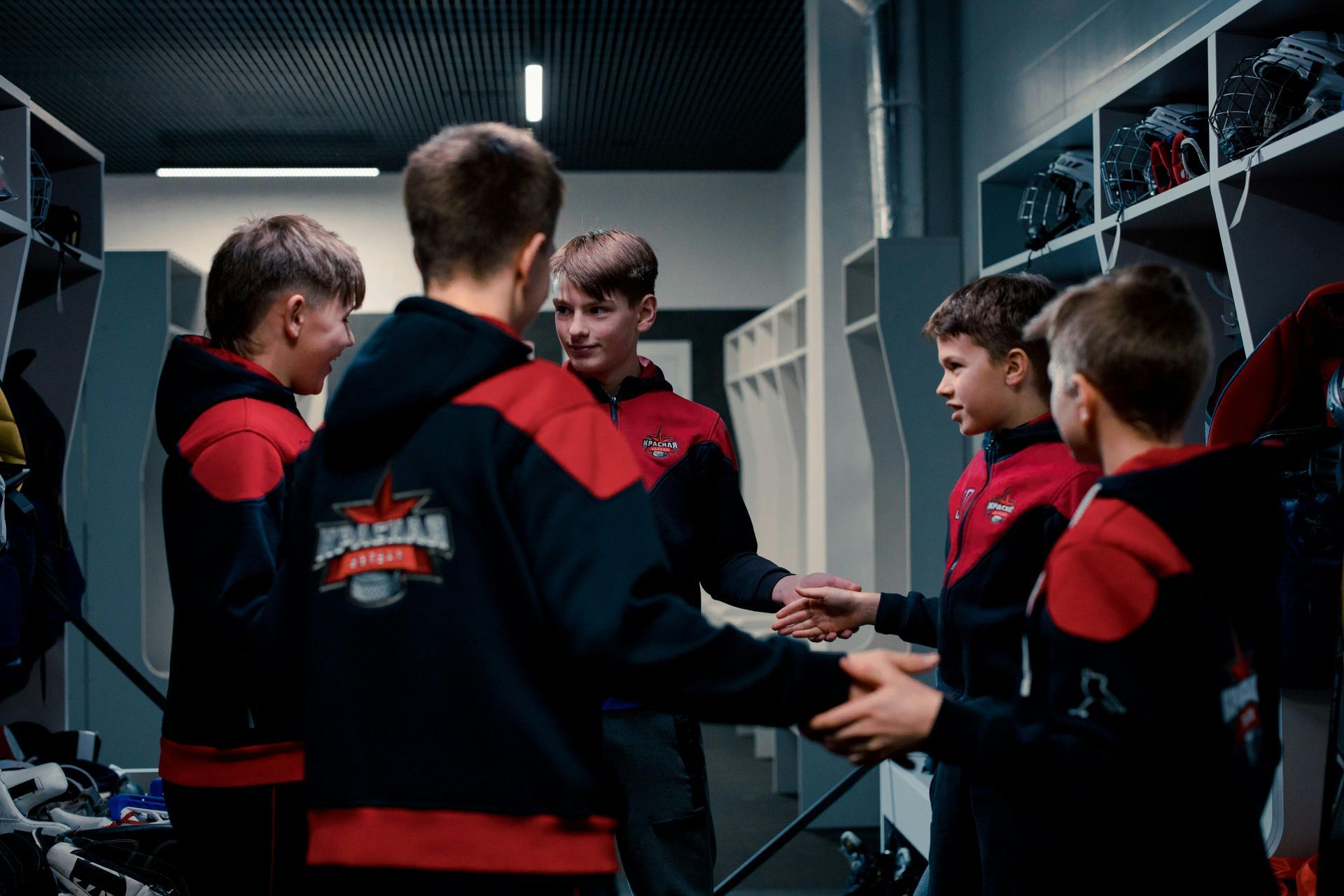 A group of young boys are shaking hands in a locker room.