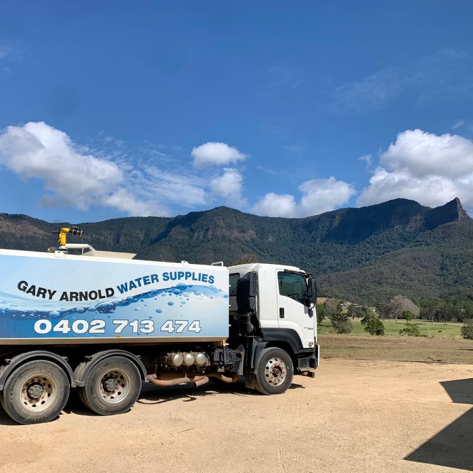 A Truck Is Parked In A Dirt Field With Mountains In The Background — Gary Arnold Water Supplies in Uki, NSW