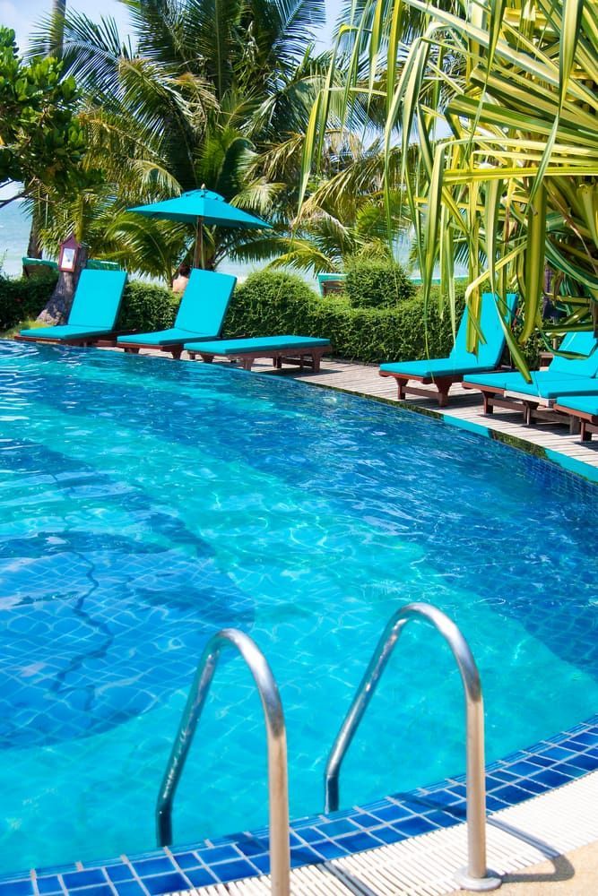 A Large Swimming Pool Surrounded By Blue Chairs And Umbrellas — Gary Arnold Water Supplies in Uki, NSW