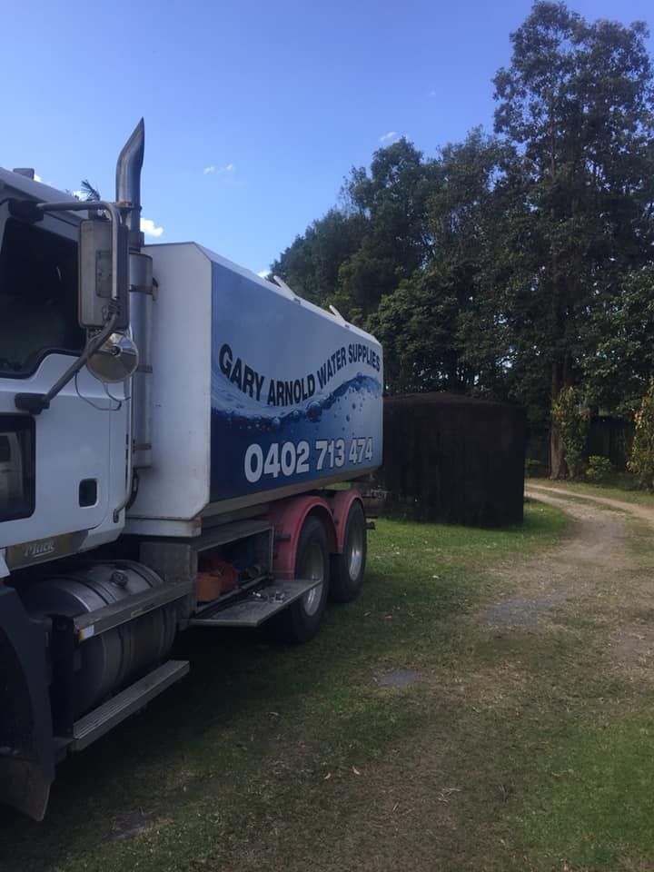 A Large White Truck Is Parked In A Grassy Field — Gary Arnold Water Supplies in Tweed Coast, NSW