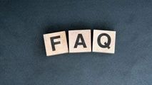 The letters F, A, and Q on wooden blocks arranged in a row against a dark, textured background.