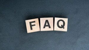 The letters F, A, and Q on wooden blocks arranged in a row against a dark, textured background.