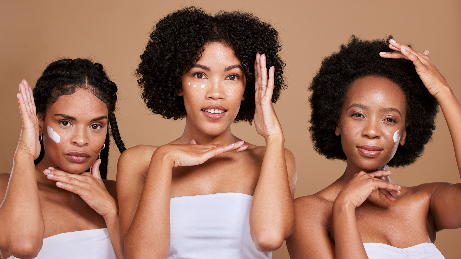 Three women are standing next to each other and applying cream to their faces.