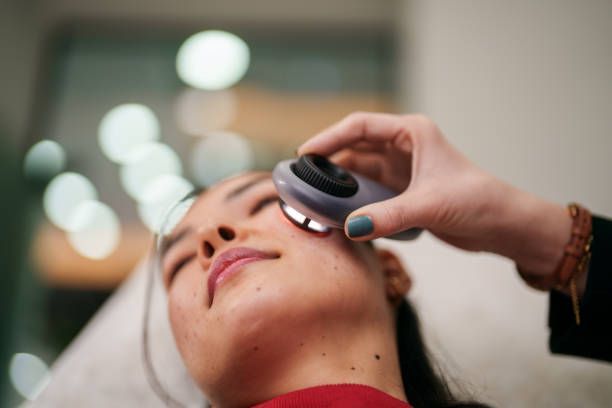 A doctor is examining a woman 's shoulder with a light.