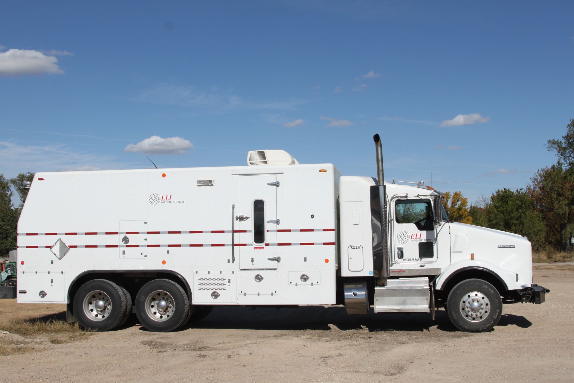 A white truck is parked in a dirt field with ELI logo on the side door
