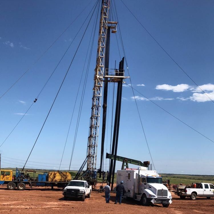 A truck is parked in front of a large tool for oil
