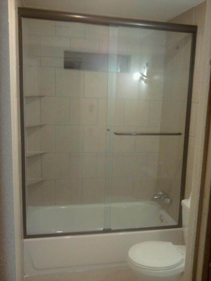 A bathroom with a bathtub , toilet and sliding glass shower door.