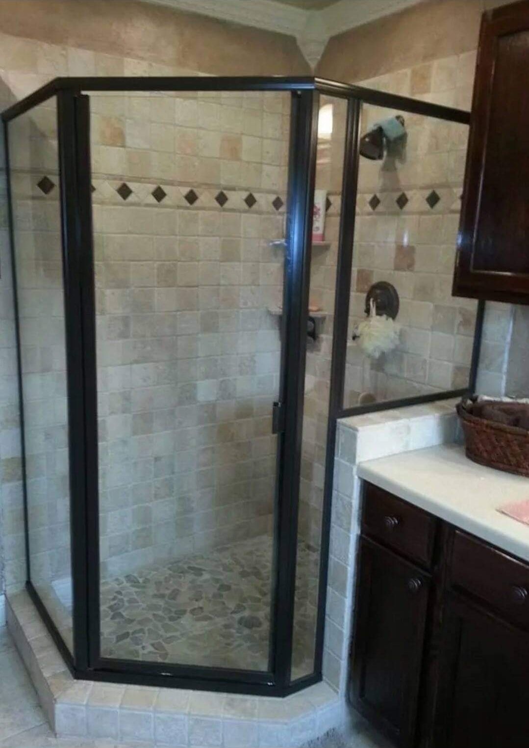 A bathroom with a walk in shower with a black frame.