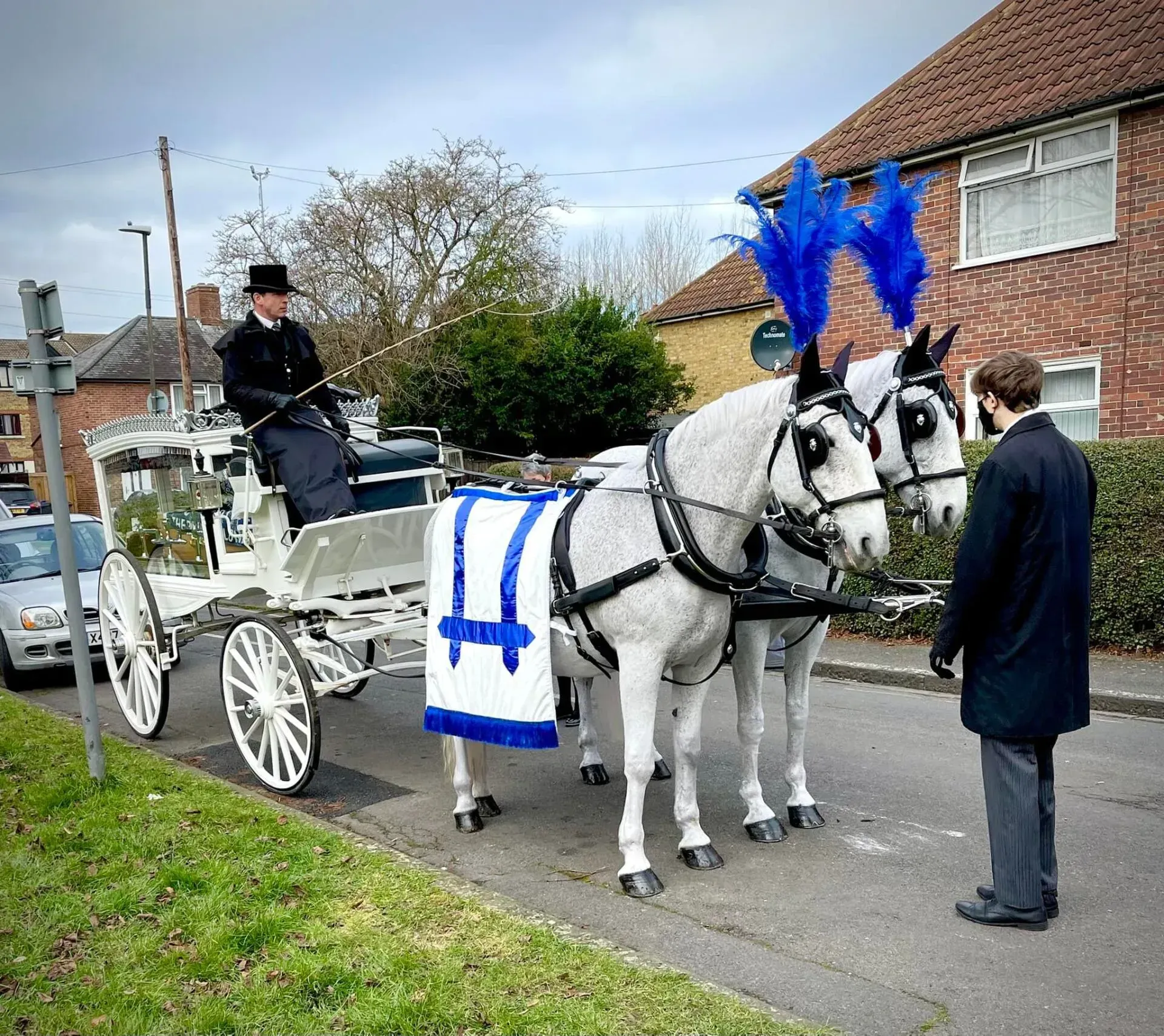 A man is standing next to a horse drawn carriage