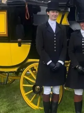 A man and a woman are standing in front of a horse drawn carriage.