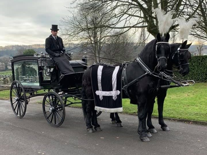 A man in a top hat is driving a horse drawn carriage.