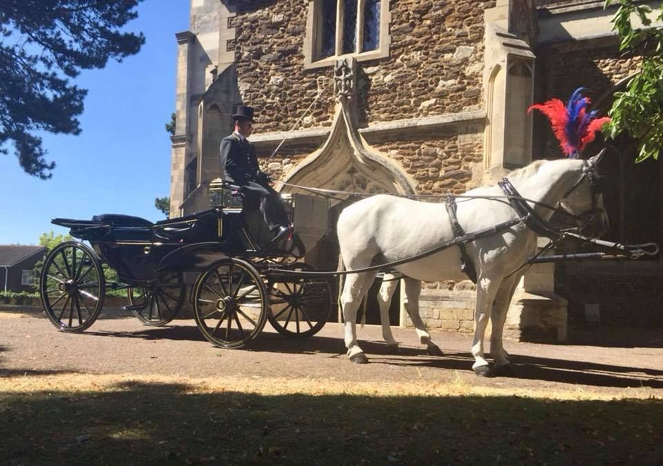 A horse drawn carriage is parked in front of a stone building.
