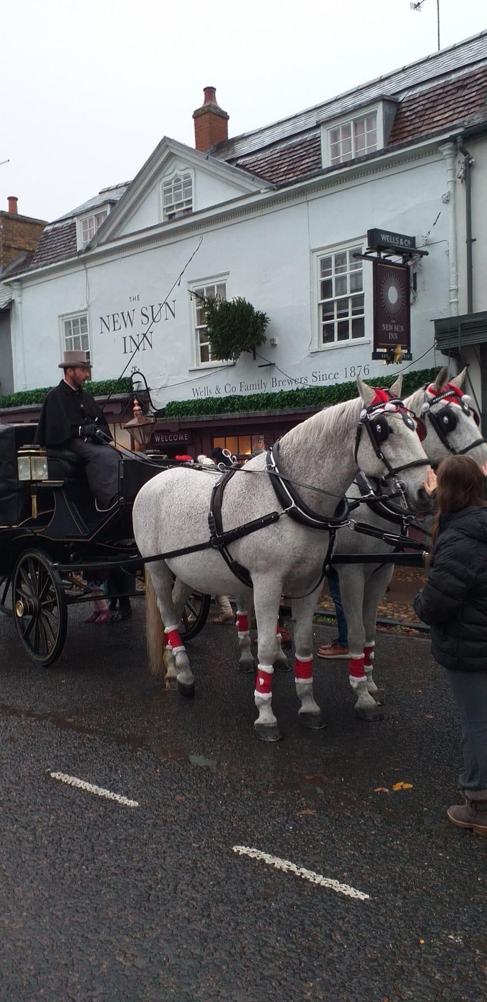A man is driving a horse drawn carriage down a street