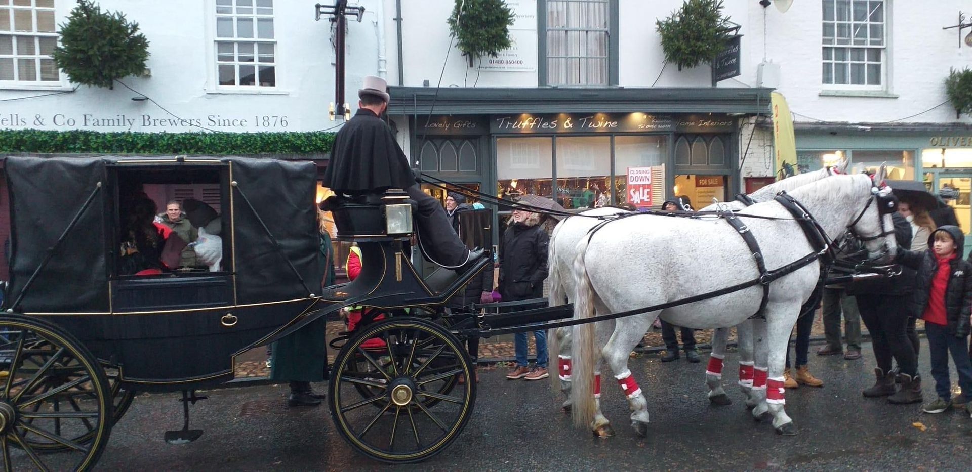 A horse drawn carriage is pulled by two white horses