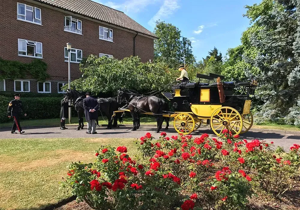 A horse drawn carriage is parked in front of a brick building