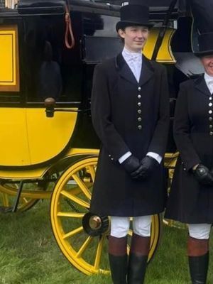A man and a woman are standing in front of a horse drawn carriage.