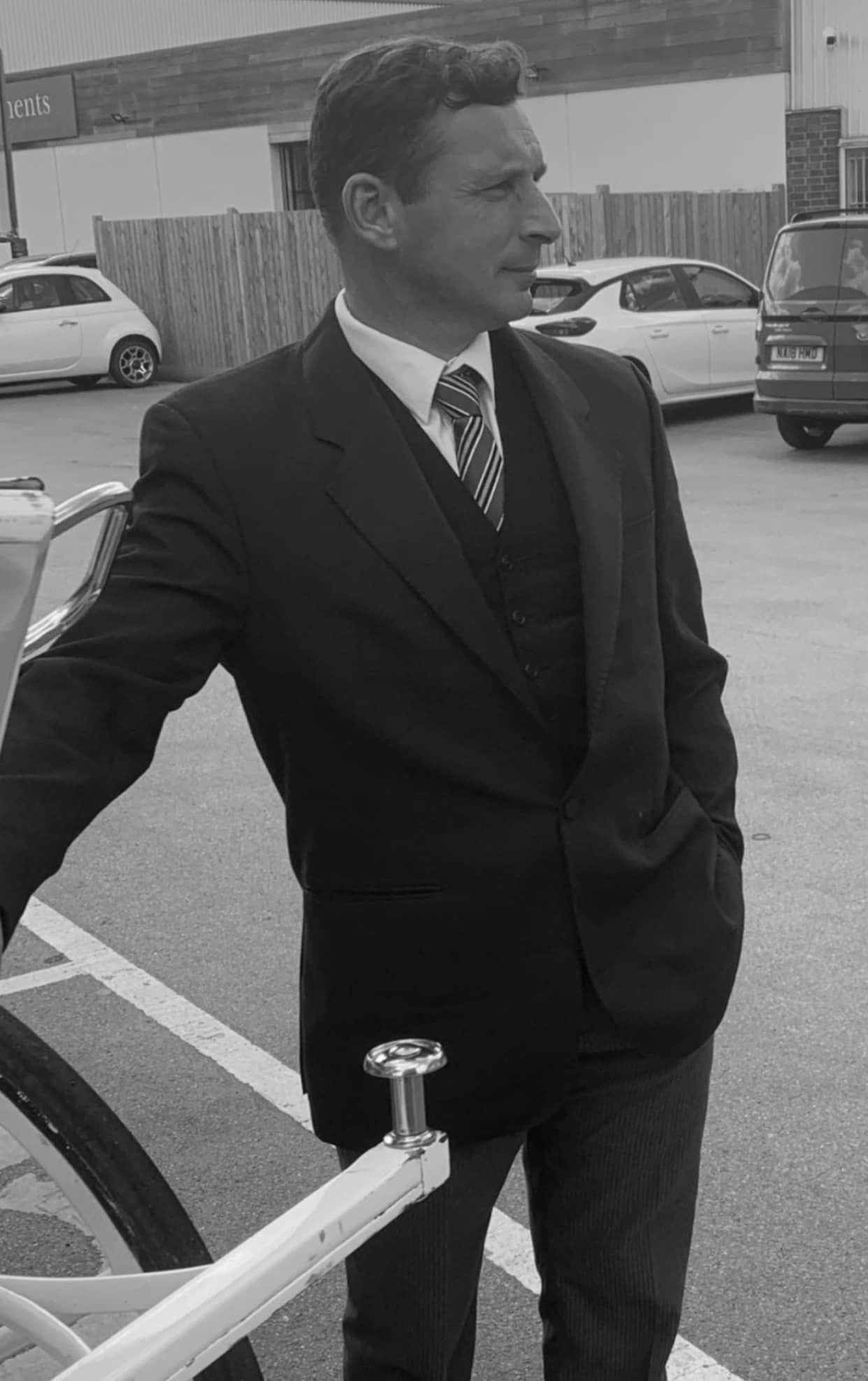 A man in a suit and tie is standing in a parking lot