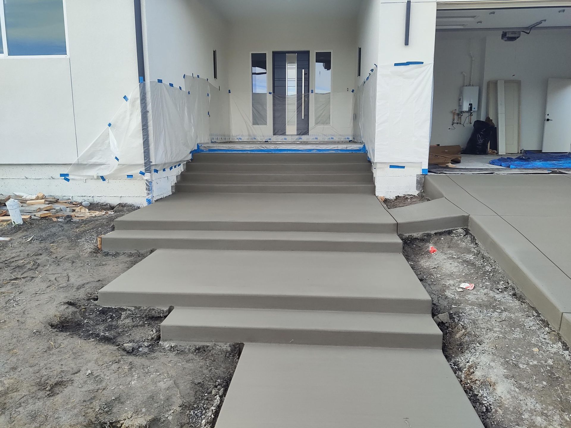 A concrete walkway leading up to a house with a fence and trees.