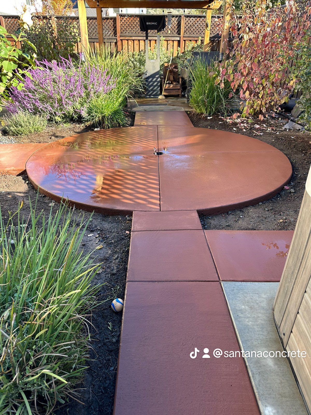 A circular walkway in a garden with a gazebo in the background.