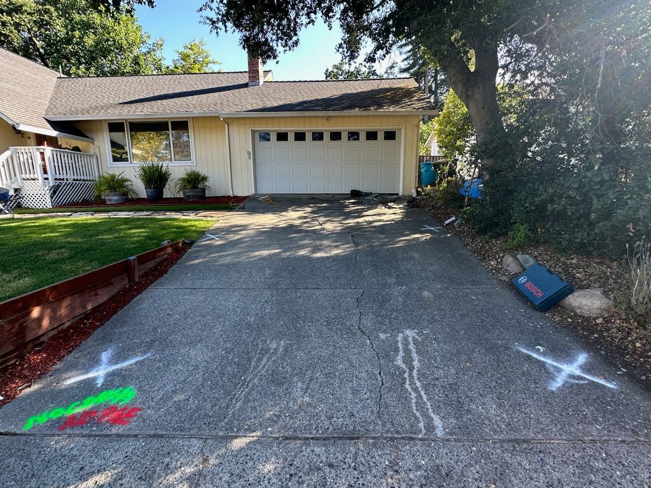 A driveway in front of a house with chalk drawings on it