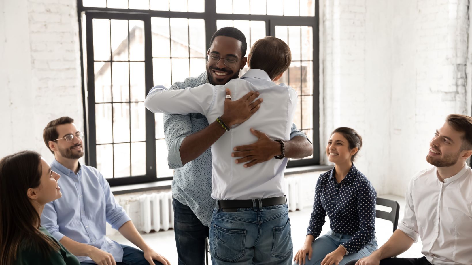 A group of people are hugging each other in a room.