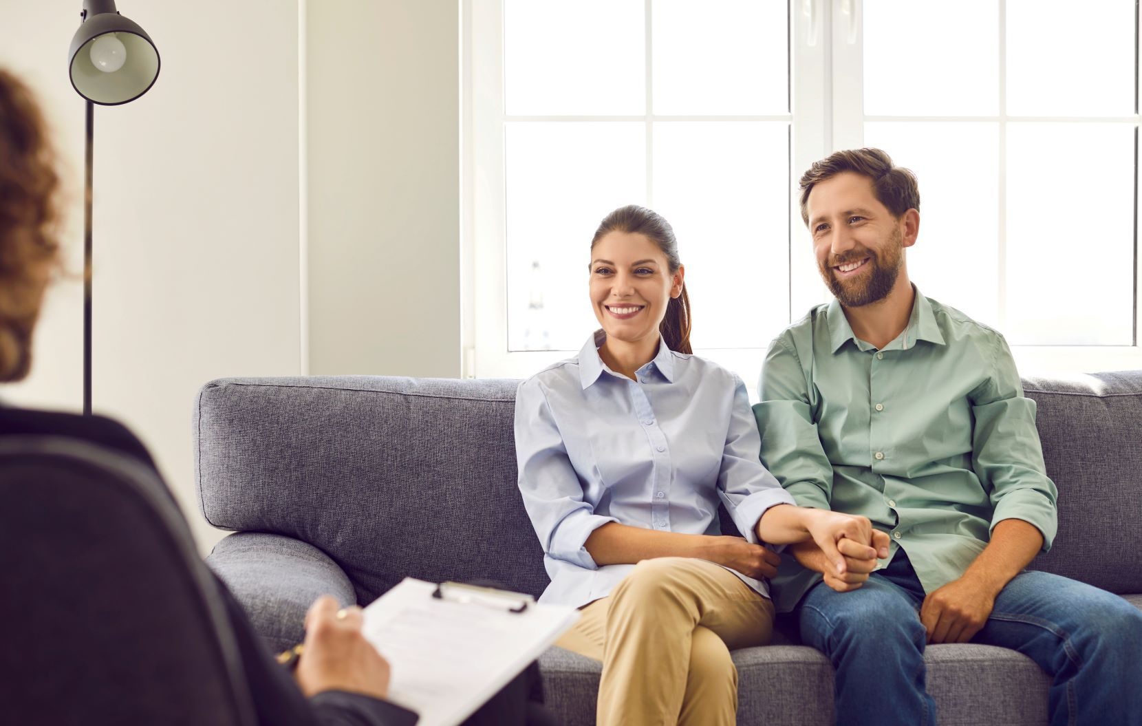 A man and a woman are sitting on a couch talking to a counselor.