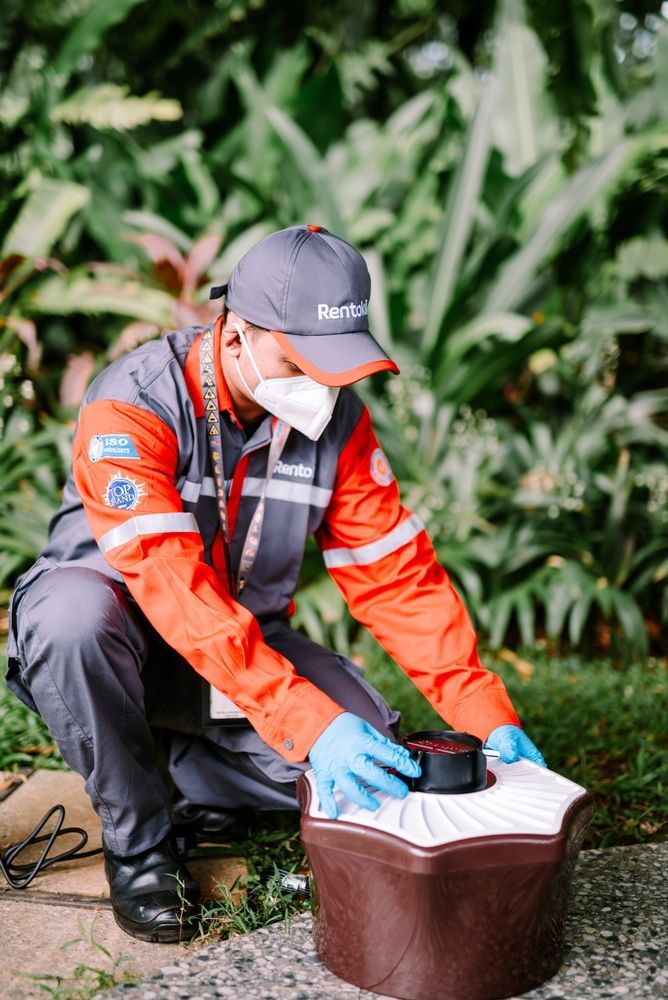 A man wearing a mask and gloves is kneeling down next to a bucket.
