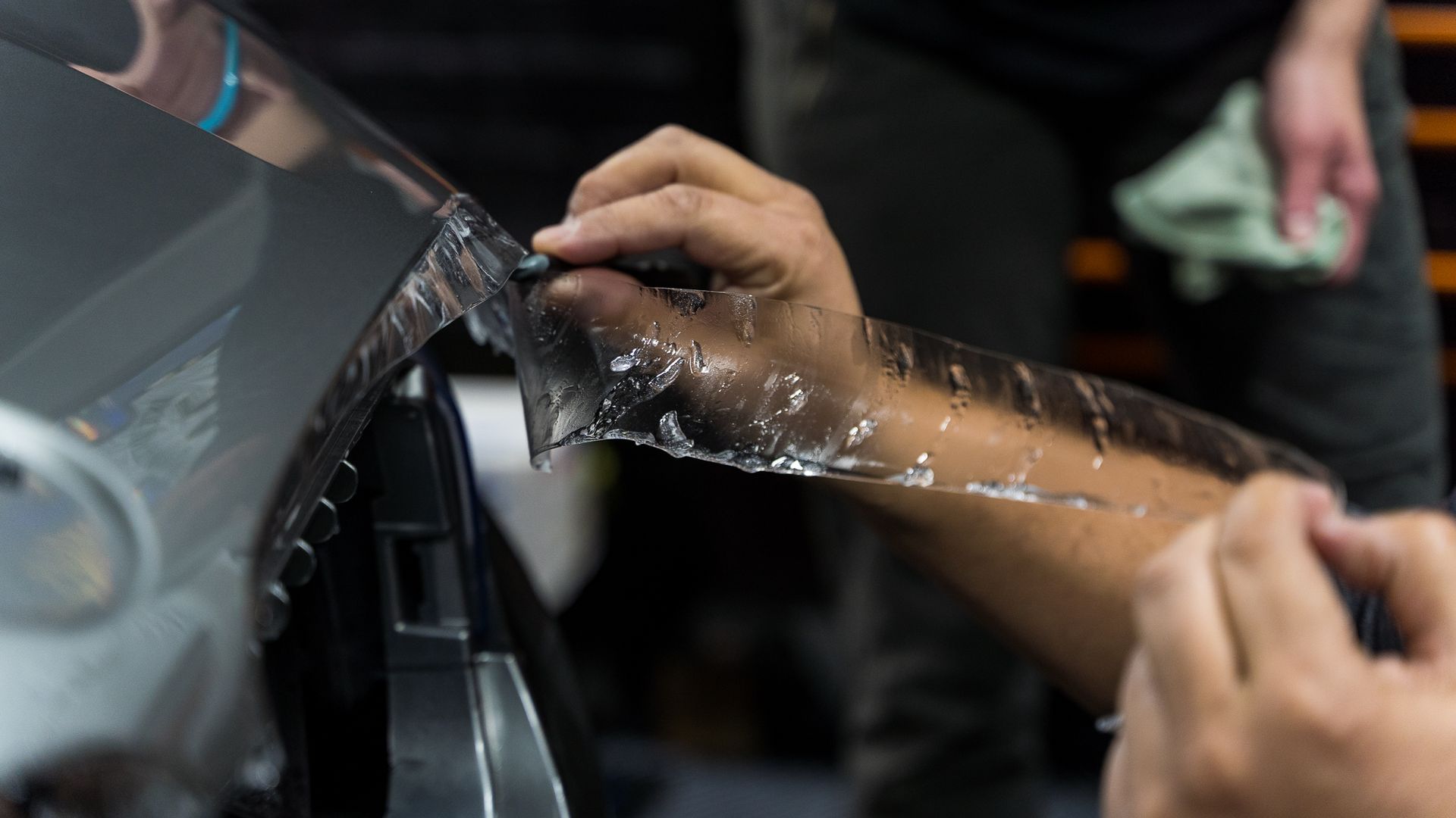 A person is applying paint protection film to a vehicle.