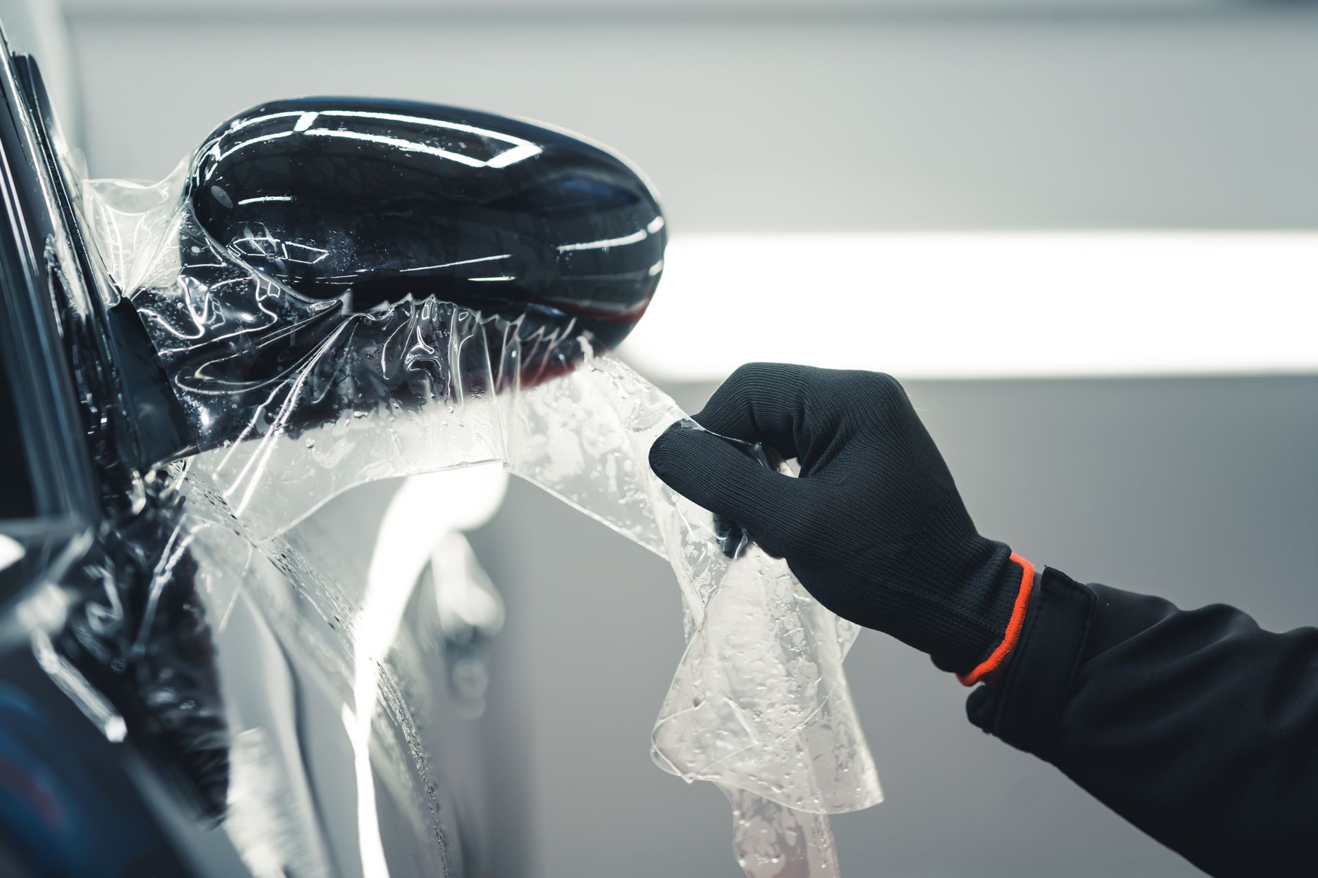 A person is wrapping a car with plastic wrap.