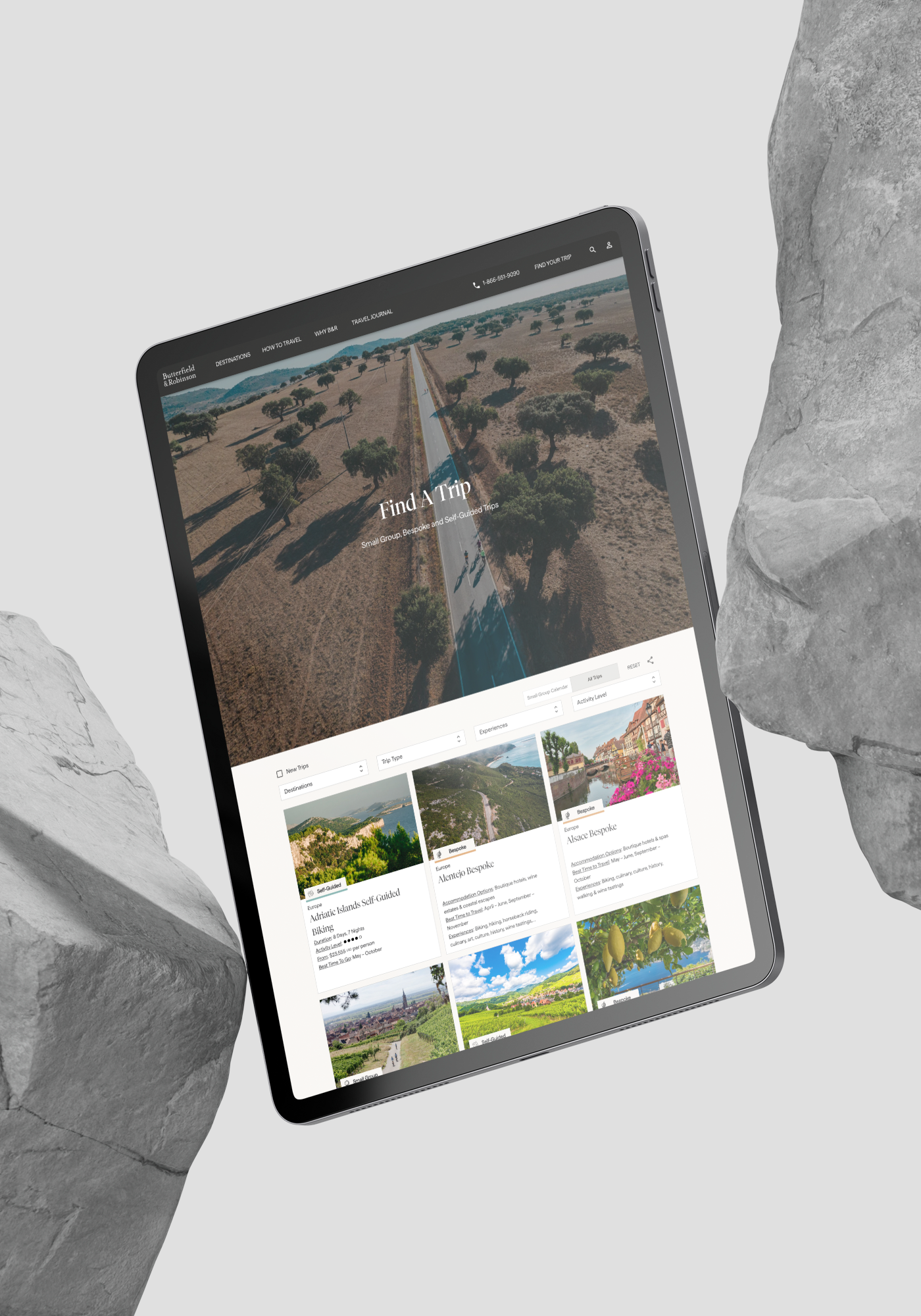 Tablet floating among rocks, showing a travel website with landscape photos and a large hero image.