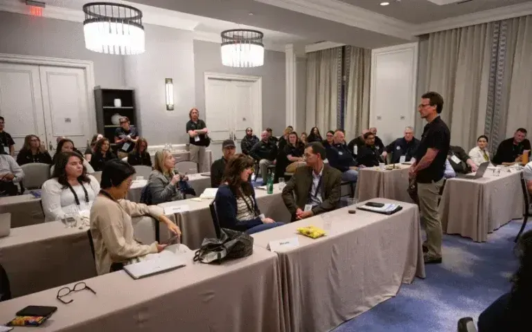 Conference room presentation with seated audience watching a speaker at the front