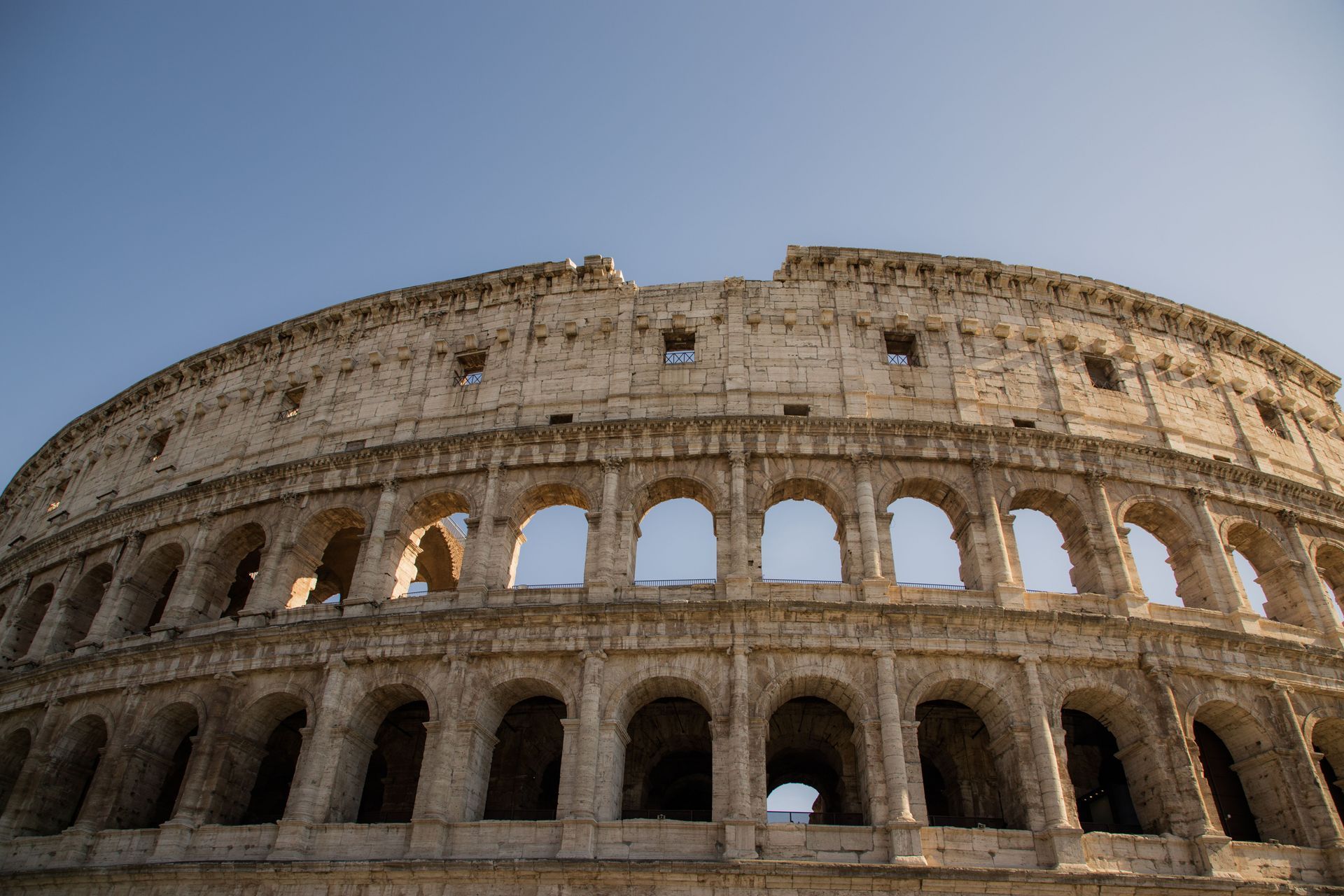 Low-angle view of the Colosseum in Rome against a blue sky