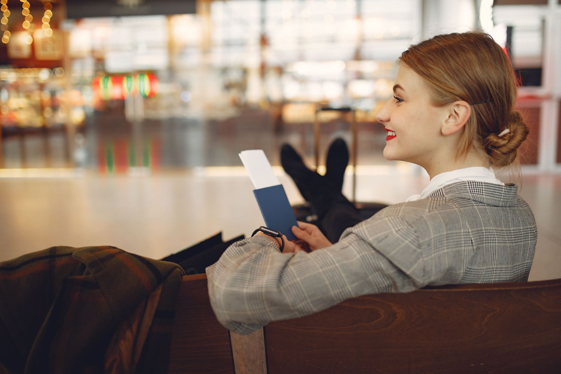 Woman relaxing on a couch, smiling and reading a book in a softly lit modern lounge.