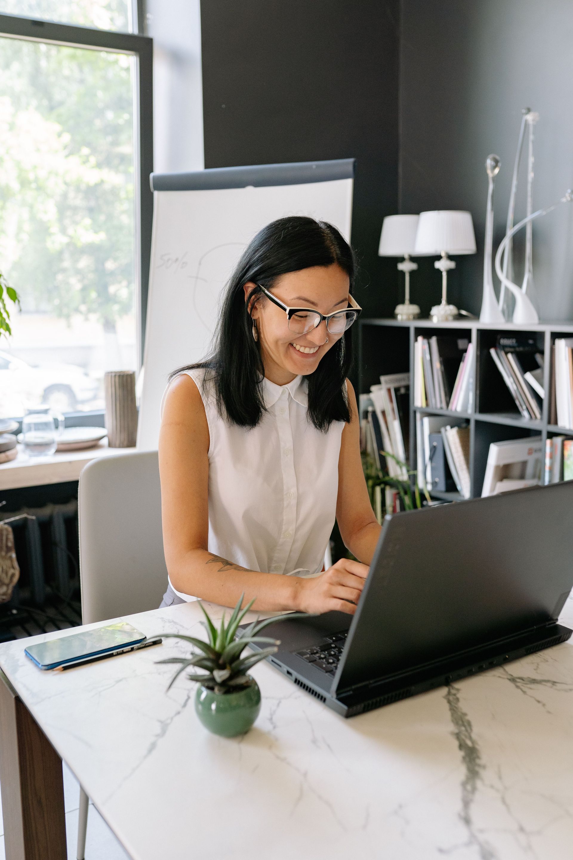 Person working on a laptop at a desk in a bright home office